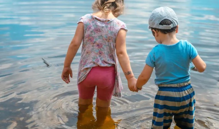 two children stepping into shallow water. 