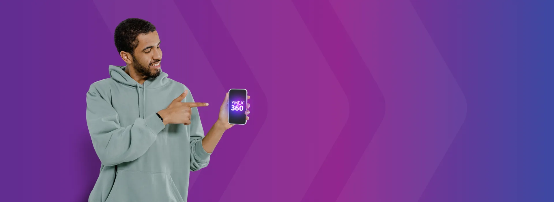 A man holding a phone with the YMCA360 app.